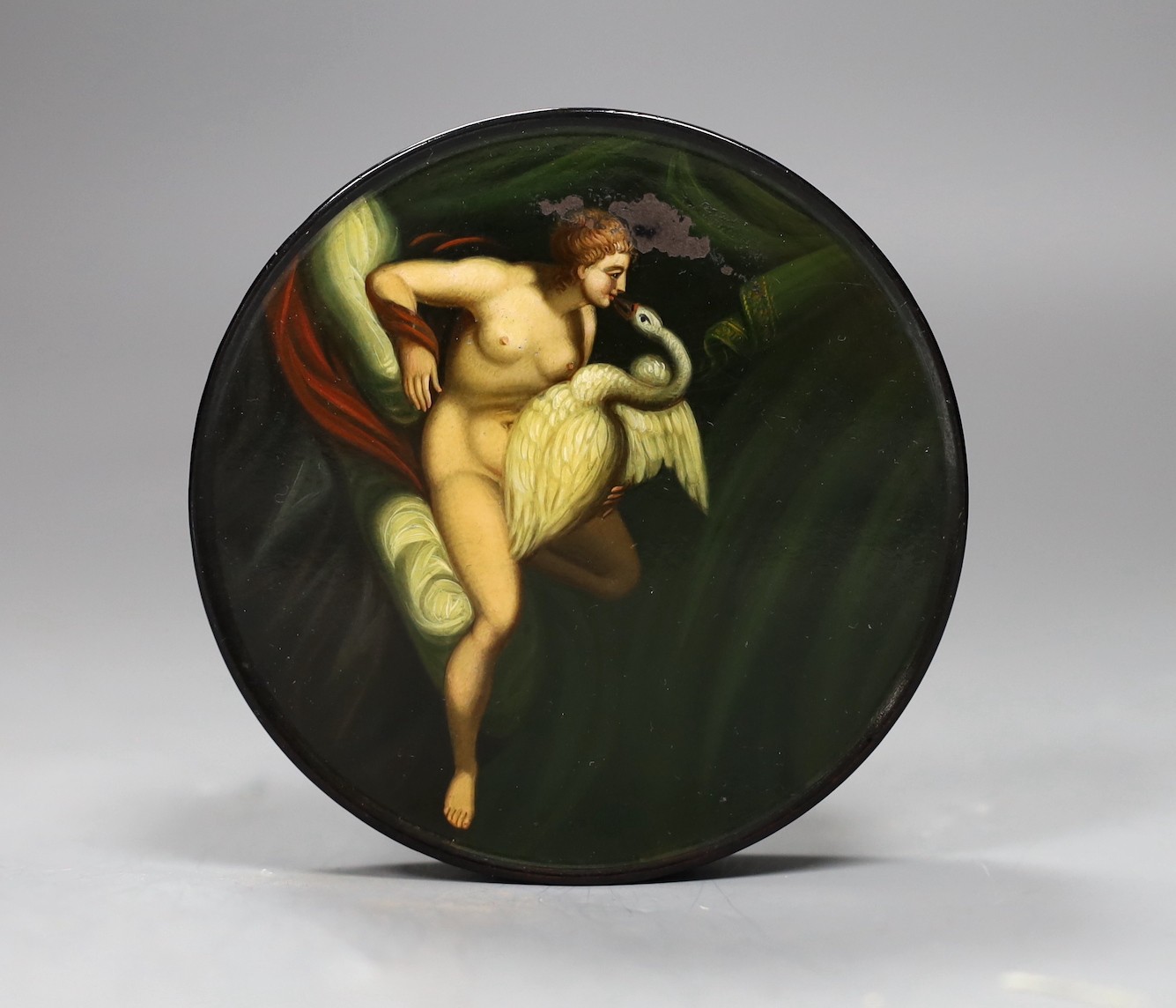 A 19th century ‘Leda and the Swan’ painted circular papier mache snuff box, 9.5cms diameter